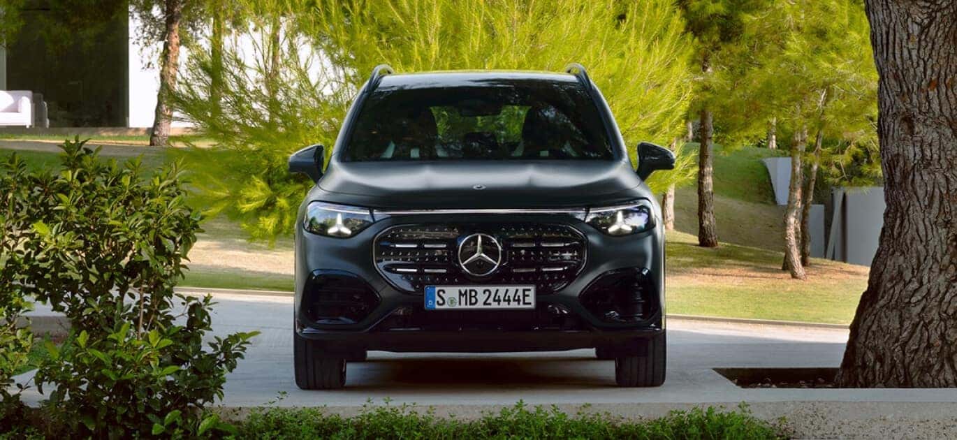 Exterior front view of a black 2027 Mercedes-Benz Electric GLB SUV parked on a tree-lined residential street.
