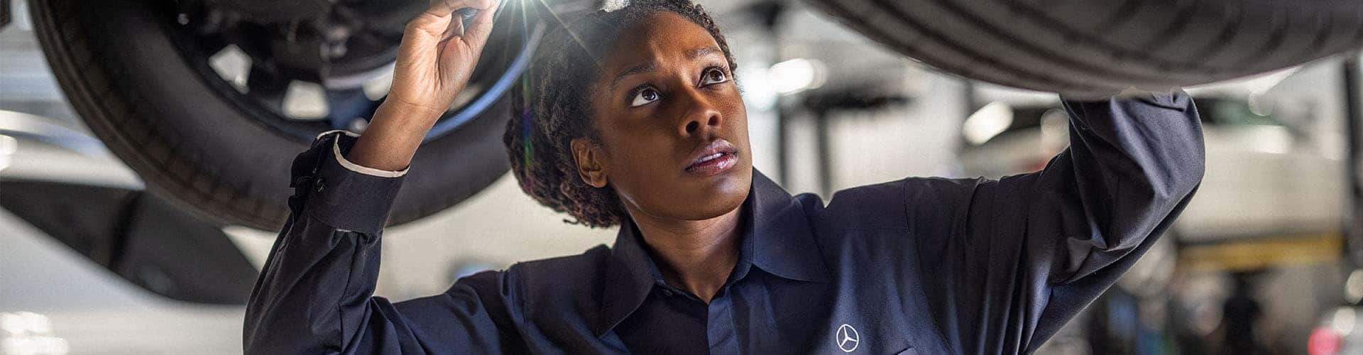 Mercedes-Benz technician inspects underneath a car.