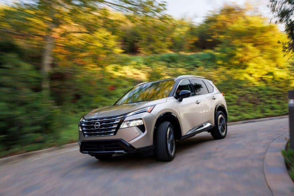 An Elegant Nissan Rogue Driving Down A Hillside Road