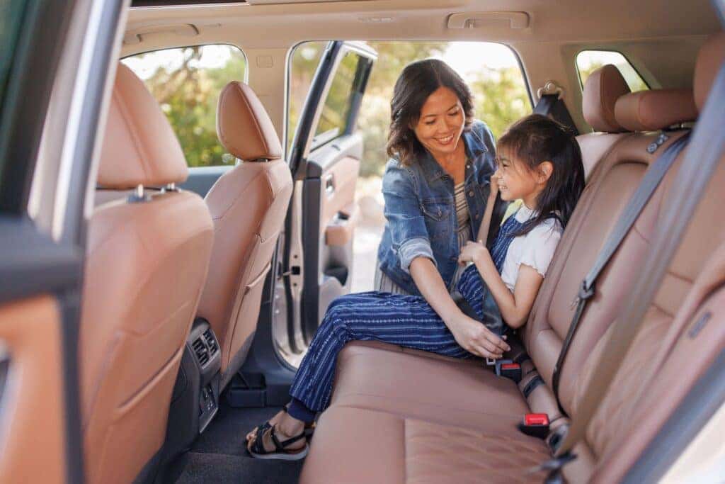 A Loving Parent Buckling Their Happy Child Into The Back Seat Of The Nissan Rogue