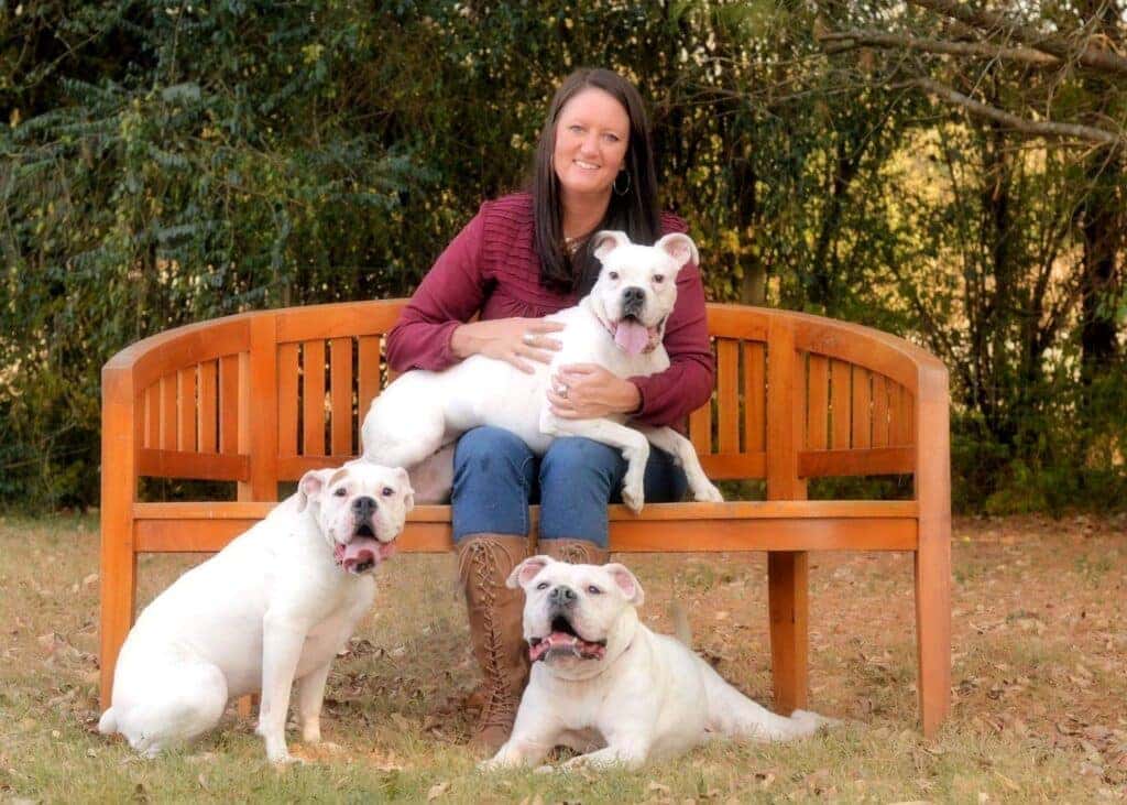 A Happy Woman Sitting On An Orange Bench With Her Three Dogs
