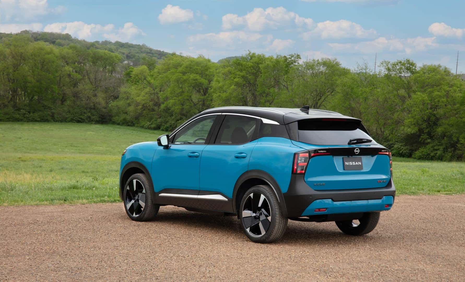 The Back Exterior Of The Spectacular And Wondrous 2024 Nissan Kicks In A Gorgeous Green Field, Near The Edge Of A Favored Forest