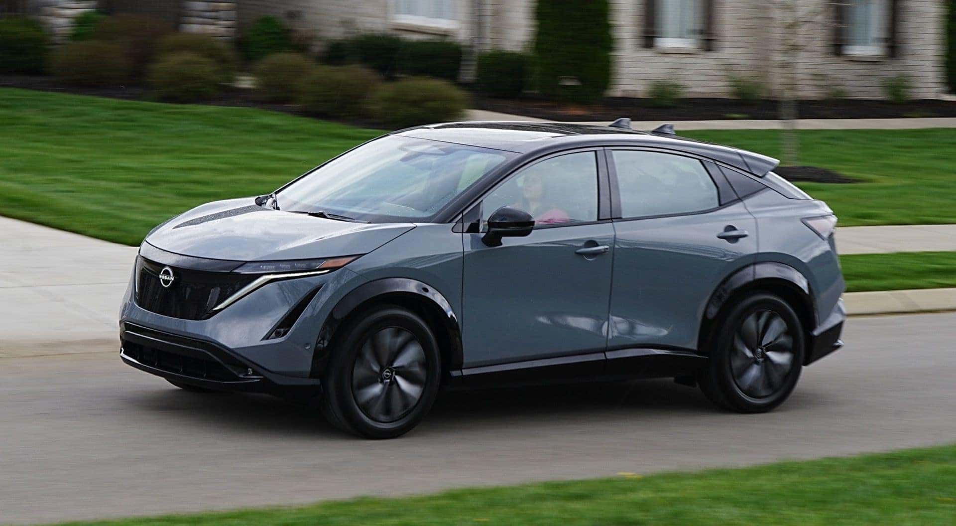 The Side Profile Of A Cruising Nissan Ariya EV In A Calm Neighborhood