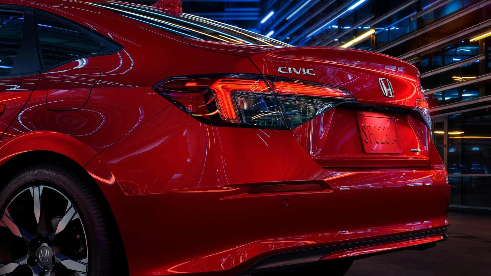 the back side rear view of a red honda civic in a warehouse at night