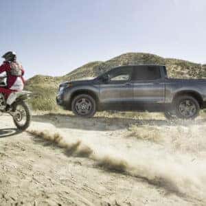 a man on a dirtbike and a honda ridgeline next to it
