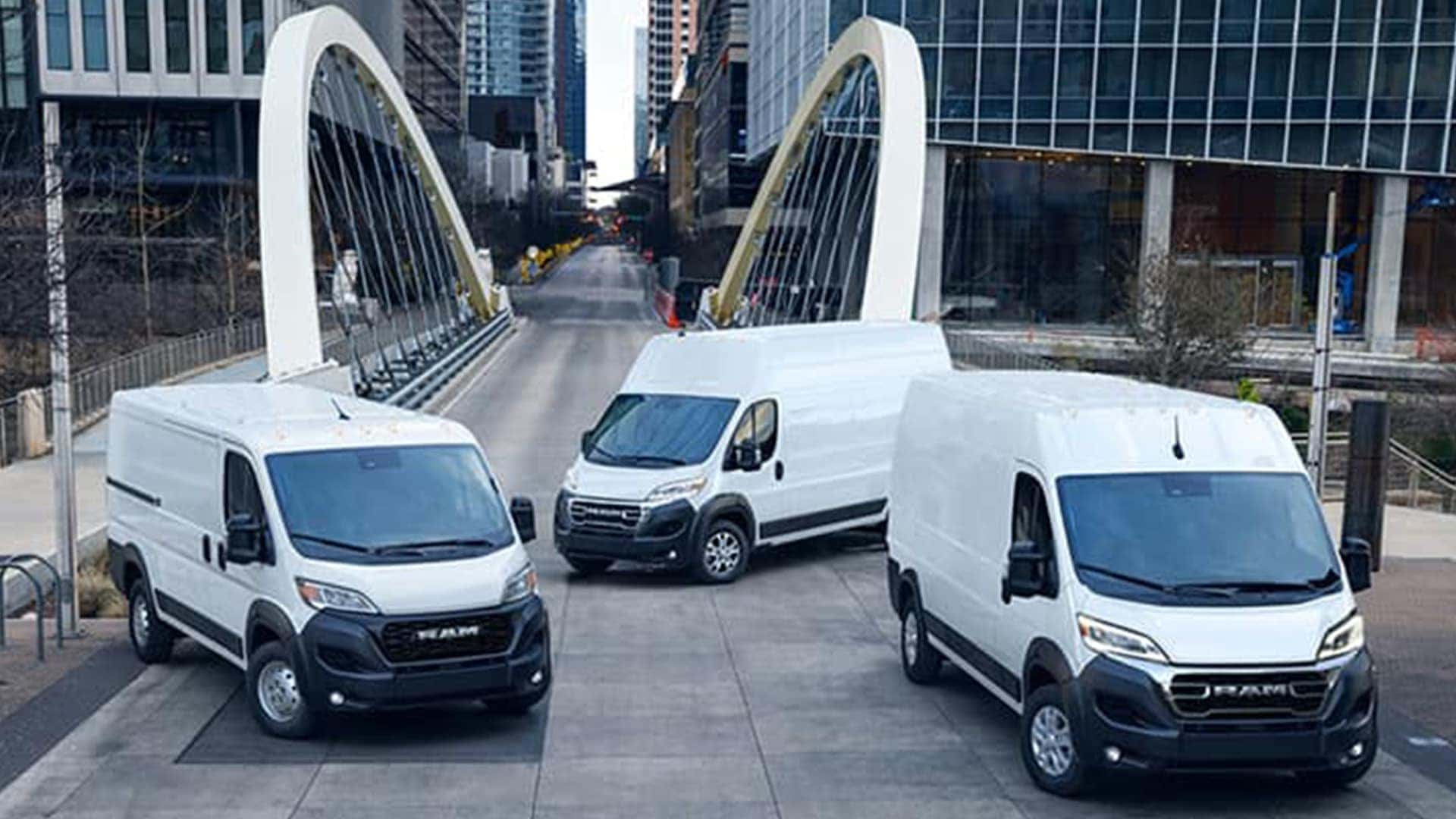 Three 2026 Ram ProMasters on a bridge in a city