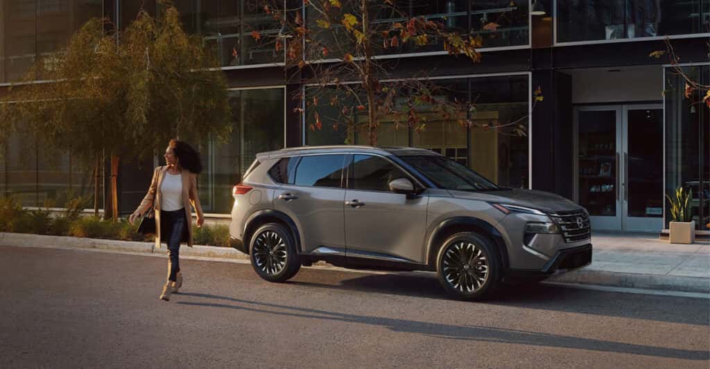 Person walking across the street next to their parked nissan rogue