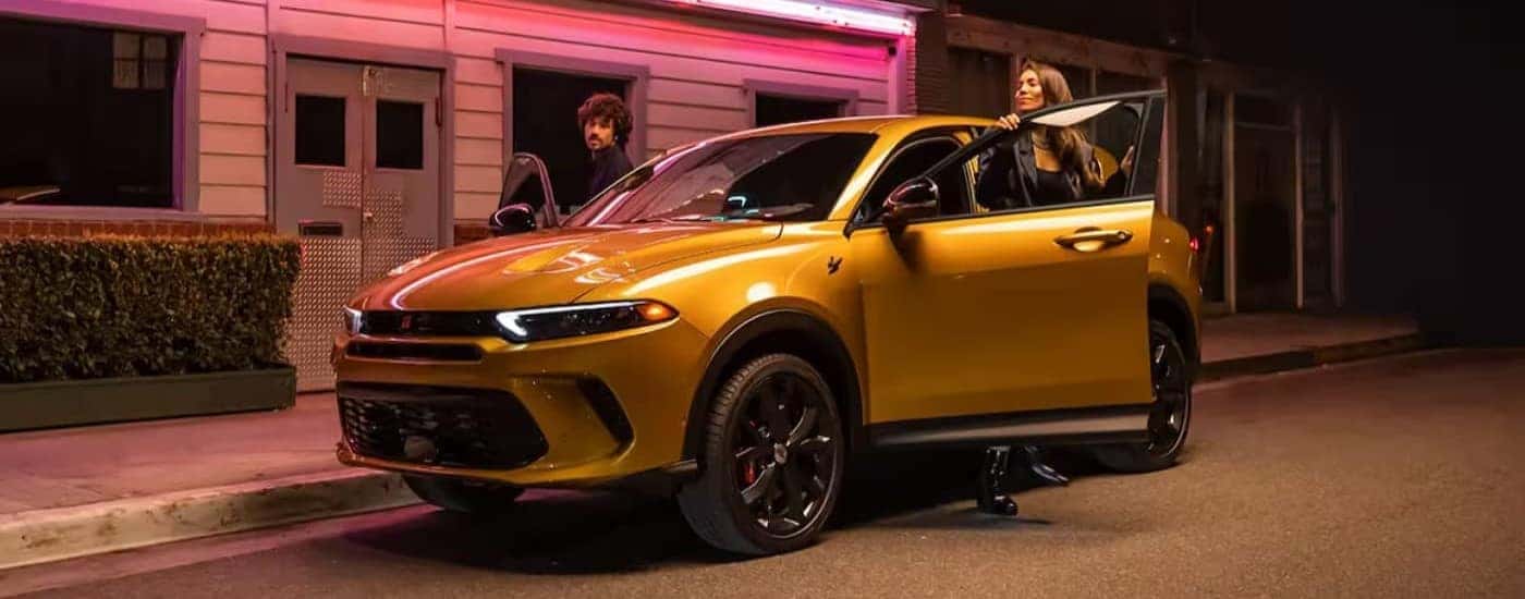 A yellow 2025 Dodge Hornet is shown parked near a neon light.