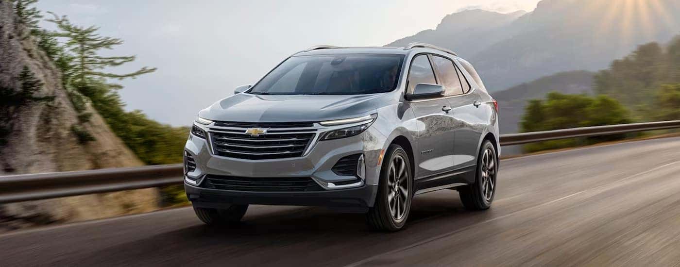 A silver 2024 Chevy Equinox Premier driving on a mountain road.