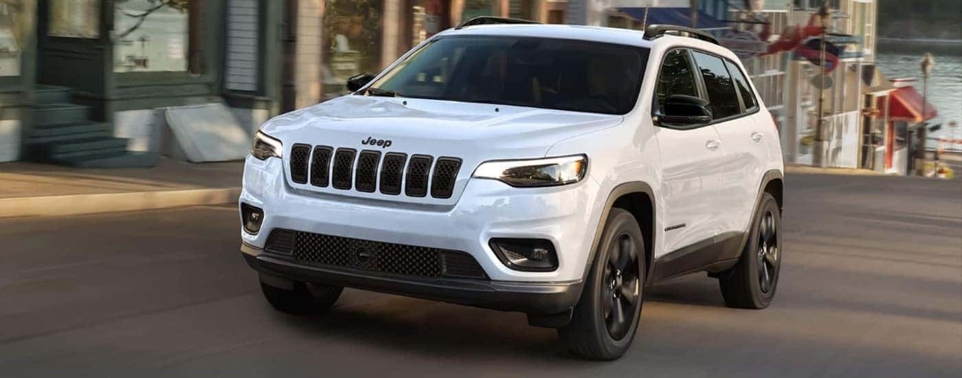 A white 2023 Jeep Cherokee Altitude Lux is driving to a Jeep dealer near Greensburg.