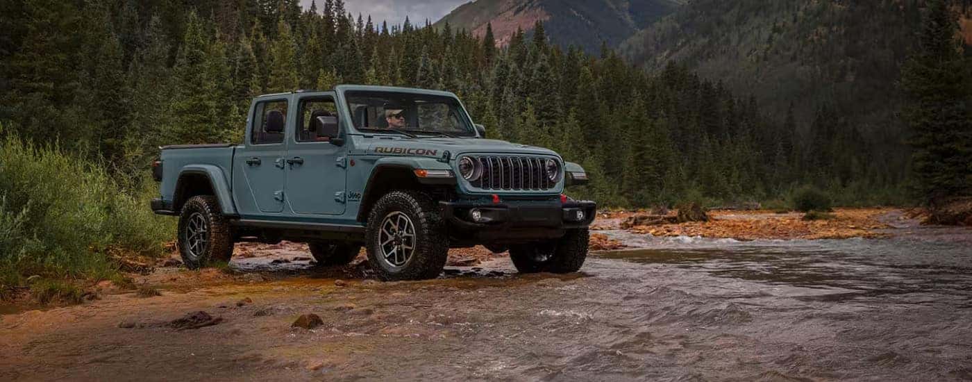 A grey 2025 Jeep Gladiator Rubicon is parked near a creek.