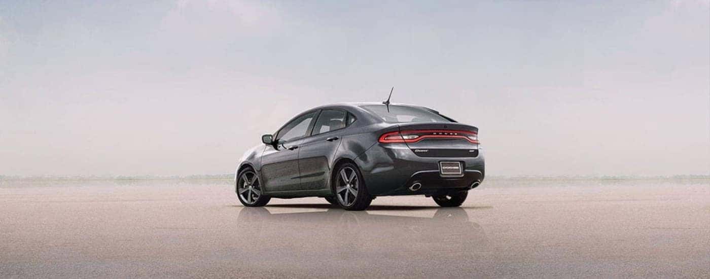 A silver 2015 Dodge Dart parked on sand.