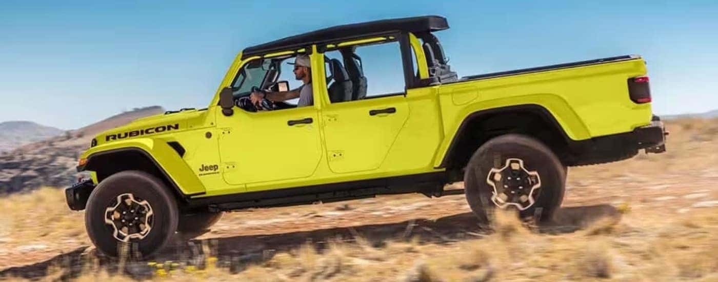 A neon yellow 2023 used Jeep Gladiator Rubicon for sale driving off-road.