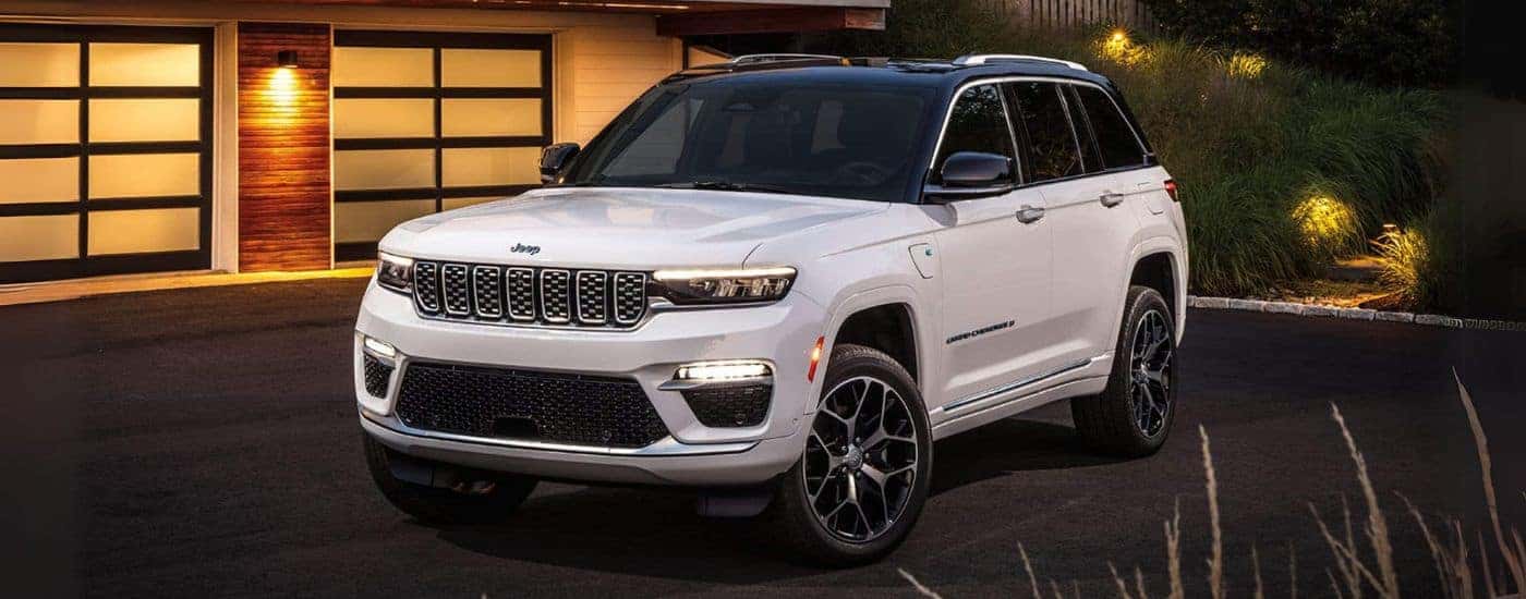 A white 2024 Jeep Grand Cherokee 4xe parked on a driveway and angled left.