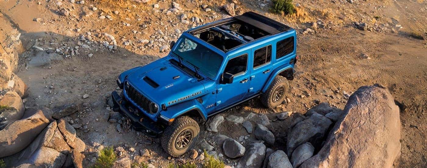 Blue 2024 Jeep Wrangler Rubicon driving off-road.