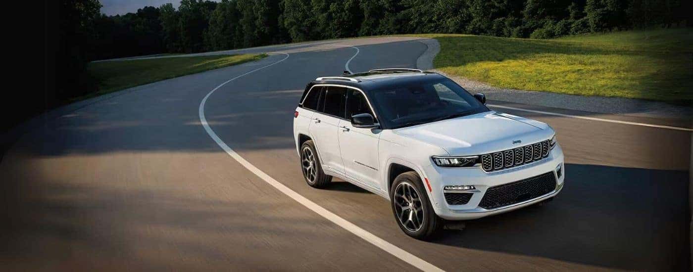 A white 2023 Jeep Grand Cherokee driving on an open road.