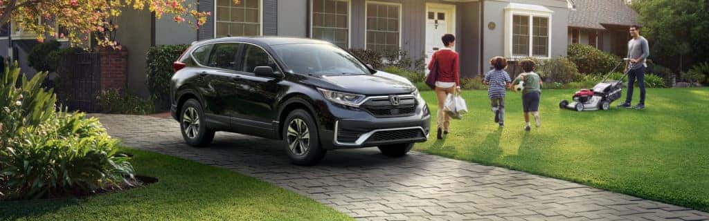 Washington Honda is a Honda Dealership in Washington near Peters Township PA | A family returning from grocery shopping by a 2021 Honda CR-V while the father mows the lawn
