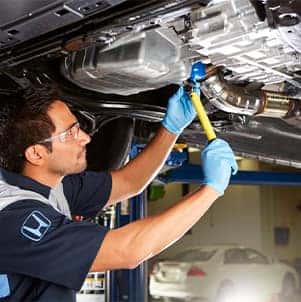 How to prepare your Honda for the winter season in Washington, PA at Washington Honda | Mechanic drains oil from car on lift