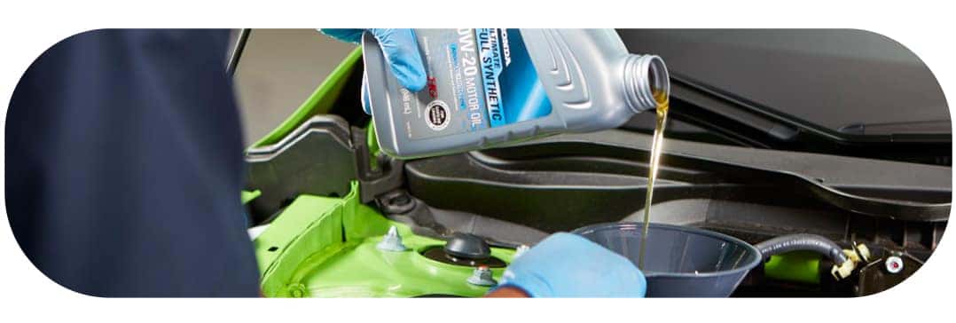 Difference between synthetic oil & conventional oil at Washington Honda | Close-up of Honda Technician adding new oil to the engine
