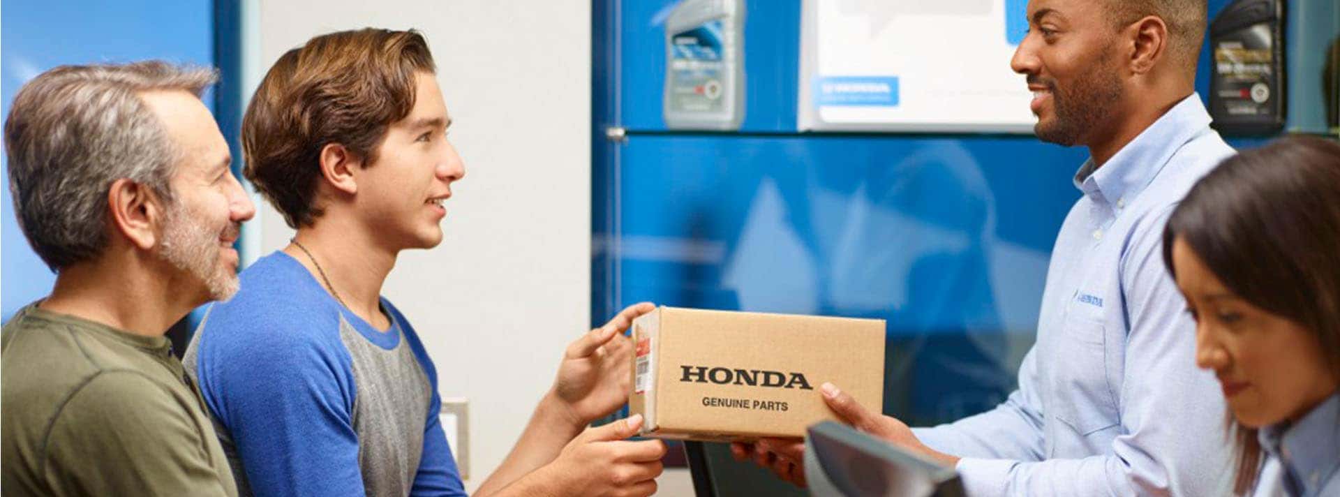3 Main Benefits of Using OEM parts for your vehicle at Washington Honda in Washington, PA | Father and Son Talking to Honda Employees at Service Counter while Son Grabs Honda Genuine Parts Box from Male Employee