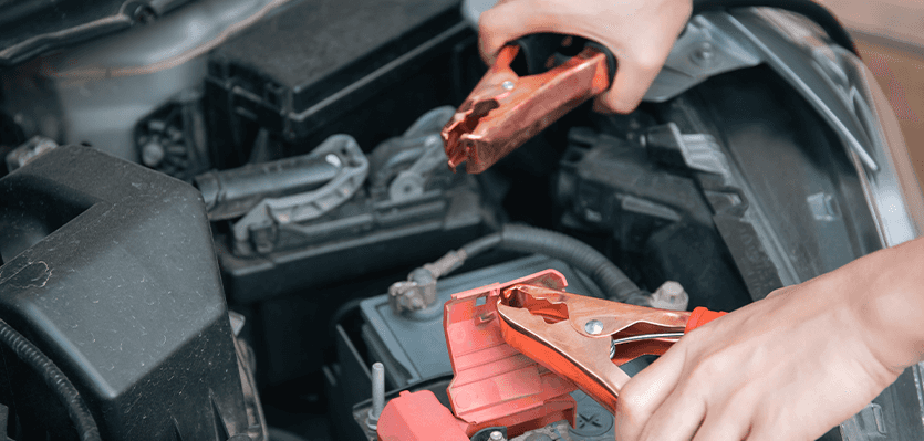 Everything You Need to Know about Your Car Battery at Washington Honda | Person holding jumper cables over a car battery